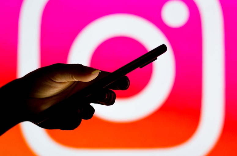 Mano con teléfono sobre un fondo con el logo de Instagram