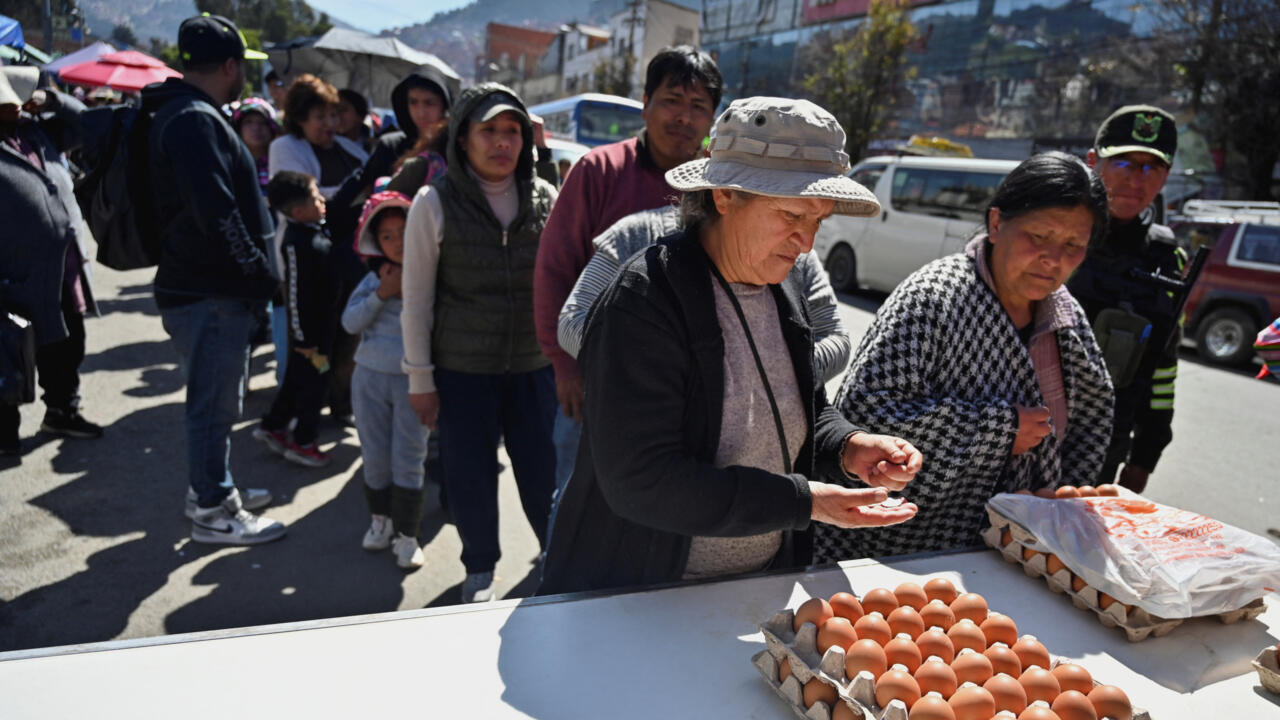 Una mujer compra un cartón de huevos mientras la gente forma largas filas para obtener productos básicos como arroz, pollo y huevos en medio de la escasez y el aumento de precios, en La Paz, Bolivia, el 24 de mayo de 2025.
