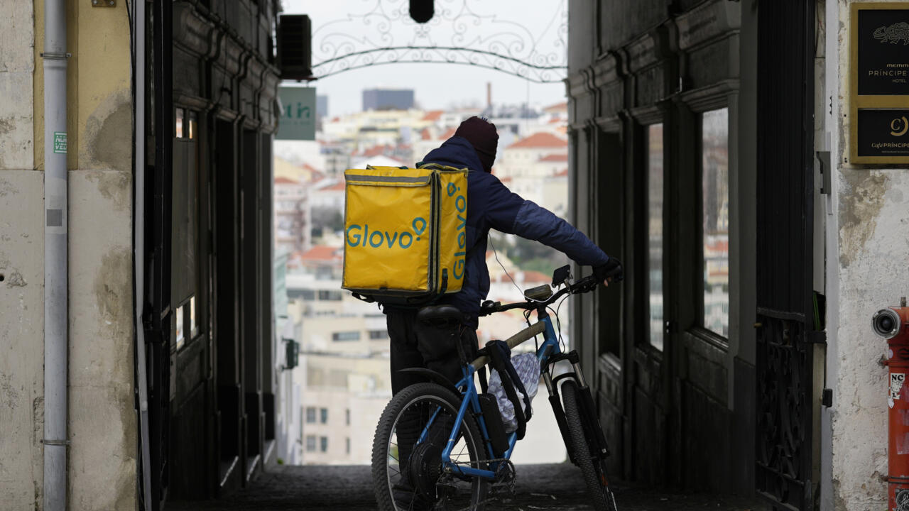 Un repartidor de guantes se detiene en un callejón de Lisboa, el lunes 27 de febrero de 2023. (AP Foto/Armando Franca)